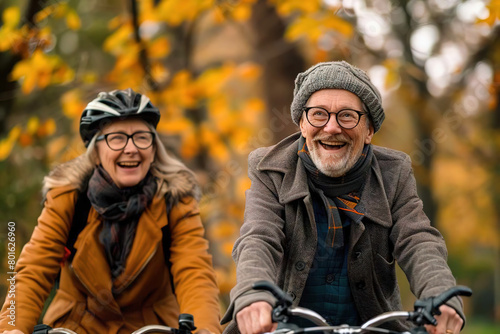 A happy old couple riding bicycles against an orange backdrop of fall foliage.