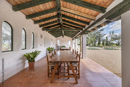 Wooden dining tables in a gallery with wooden ceilings in the patio of an Andalusian farmhouse style house