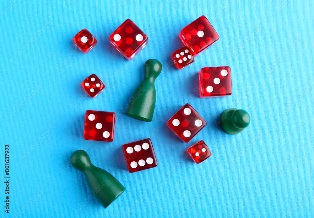 Many red dices and color game pieces on light blue background, flat lay Many red dices and color game pieces on light blue background, flat lay