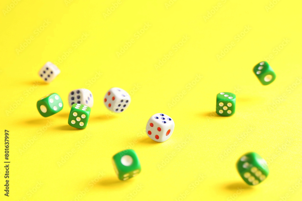 Many color game dices falling on yellow background Many color game dices falling on yellow background