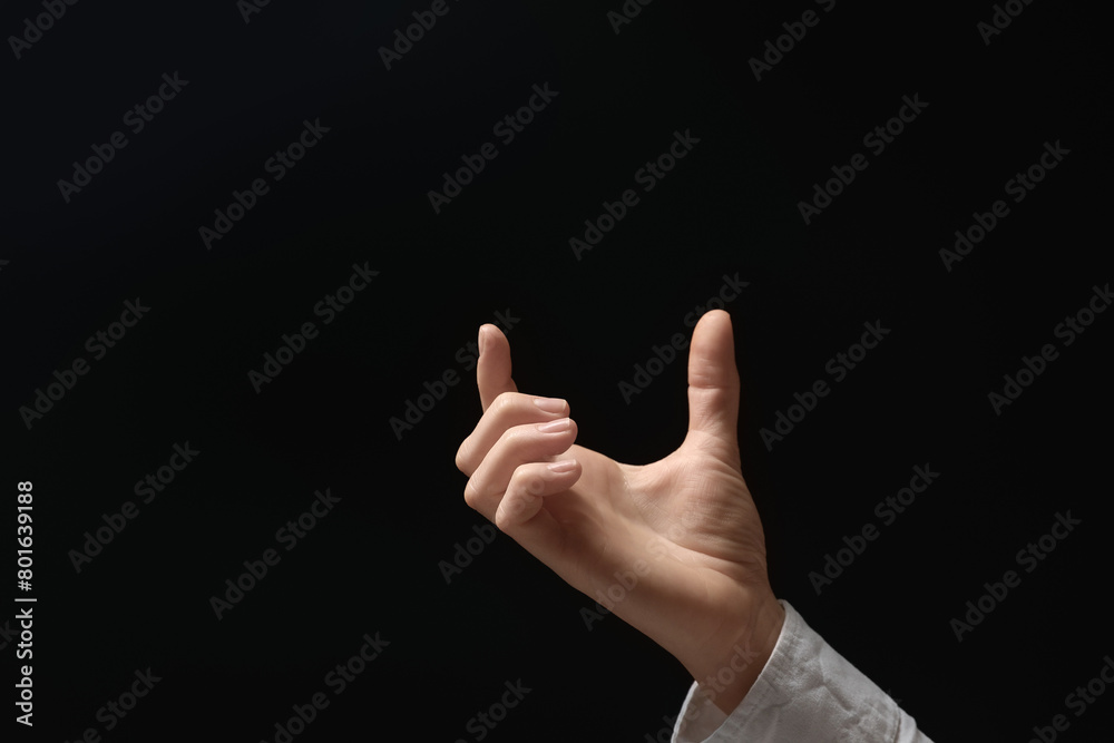 Woman holding something in hand on black background, closeup. Space for text Woman holding something in hand on black background, closeup. Space for text
