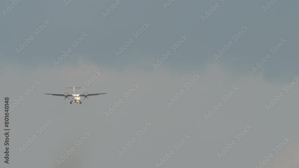 Airplane approaching. Twin-engine turboprop short-haul regional passenger aircraft. Landing airplane. Blue sky background Airplane approaching. Twin-engine turboprop short-haul regional passenger aircraft. Landing airplane. Blue sky background