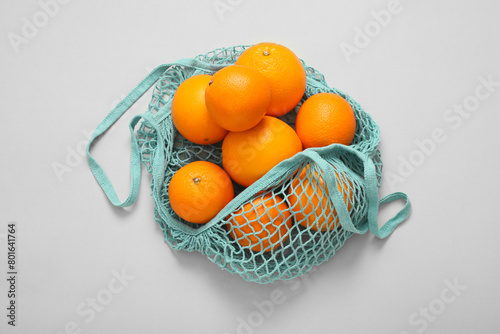 String bag with fresh oranges on light background, top view