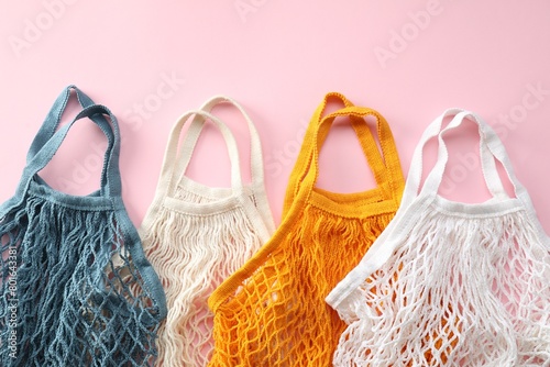 Different string bags on pink background, top view