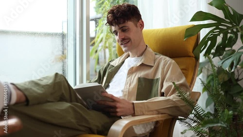 young man reading a book gesturing with expression of surprise and entertainment