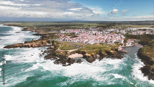 Drone flight towards Porto Covo in the west of Portugal. View of the coastline and village with traditional houses photo