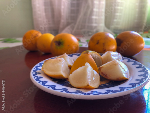 Abiu fruit cut into pieces on white porcelain plate with blue details photo