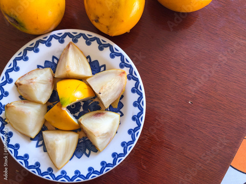 Abiu fruit cut into pieces on white porcelain plate with blue details photo