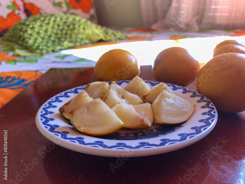 Abiu fruit cut into pieces on white porcelain plate with blue details photo