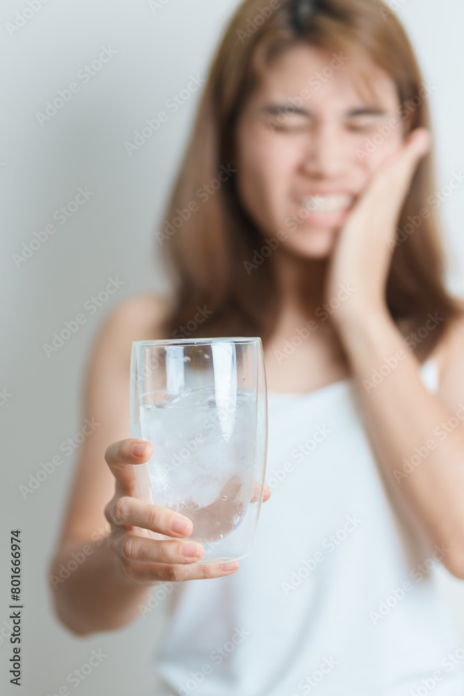 Teeth Sensitive to Cold concept. woman hold Ice Water glass and having toothache and pain after eat. Tooth Decay or Gum Disease, Grinding Teeth and Stress, Exposed Nerve Roots, Crack and Receding Gums Teeth Sensitive to Cold concept. woman hold Ice Water glass and having toothache and pain after eat. Tooth Decay or Gum Disease, Grinding Teeth and Stress, Exposed Nerve Roots, Crack and Receding Gums