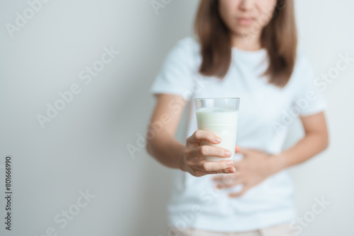 Lactose intolerance and Milk allergy concept. woman hold Milk glass and having abdominal cramps and pain when drink Cow Milk. Symptom stomach ache, Dairy intolerant, Nausea, Bloating, Gas and Diarrhea © Jo Panuwat D