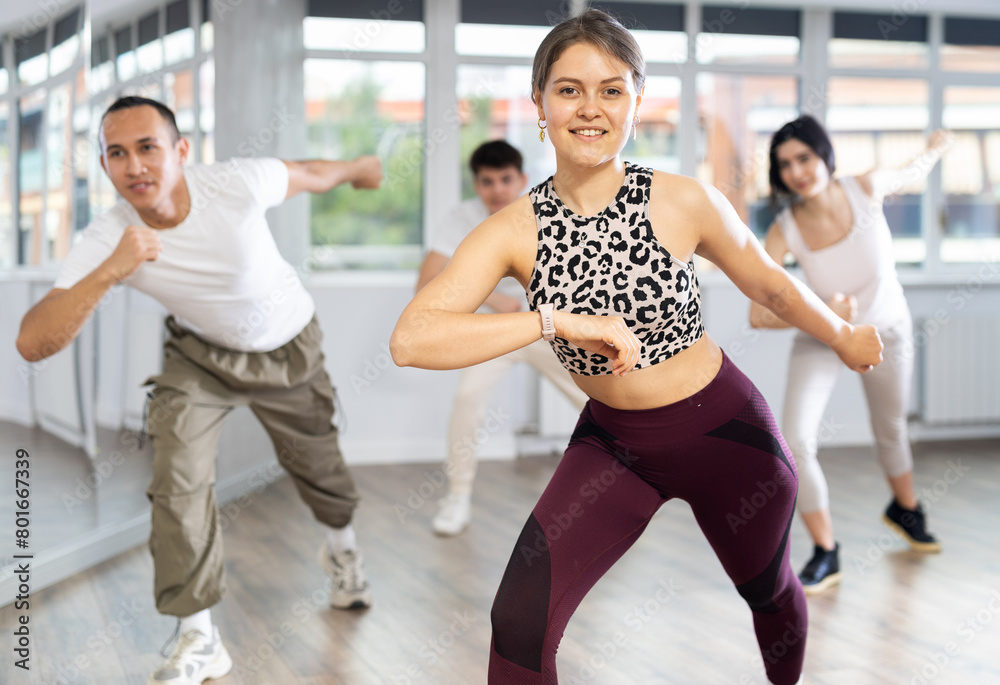 During dance workshop, girl enjoys active dancing, learns new movements, moves synchronously with participants of lesson. Concept of beautiful body through sports, dancing, and active lifestyle