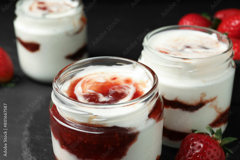 Tasty yoghurt with jam and strawberry on black table, closeup Tasty yoghurt with jam and strawberry on black table, closeup