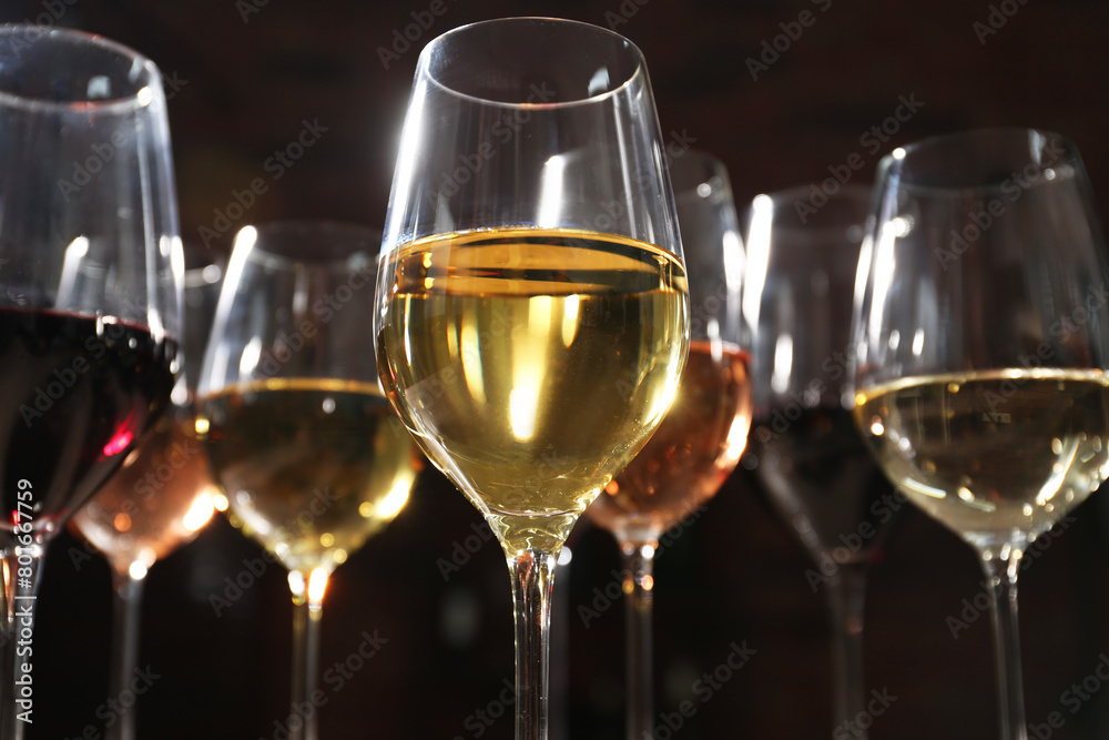 Different tasty wines in glasses against blurred background, low angle view