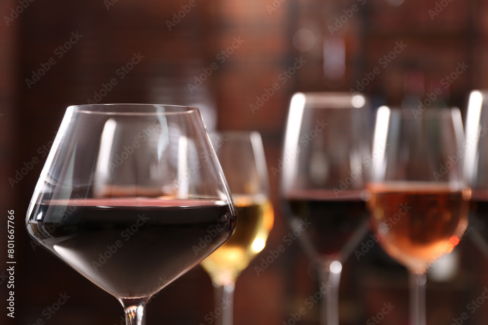 Tasty red wine in glass against blurred background, space for text