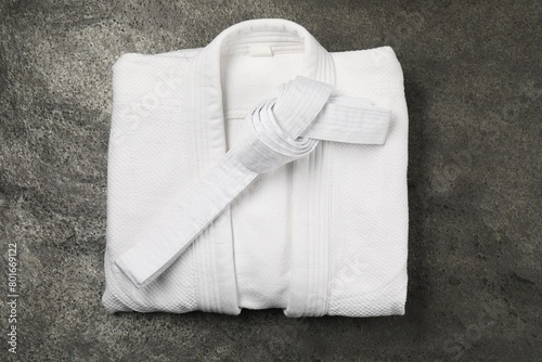 White karate belt and kimono on gray textured background, top view