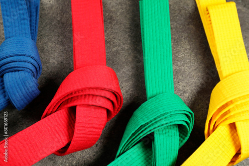 Colorful karate belts on gray background, flat lay photo