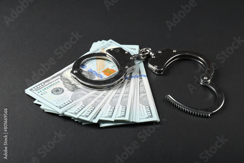 Dollars and metal handcuffs on grey table photo