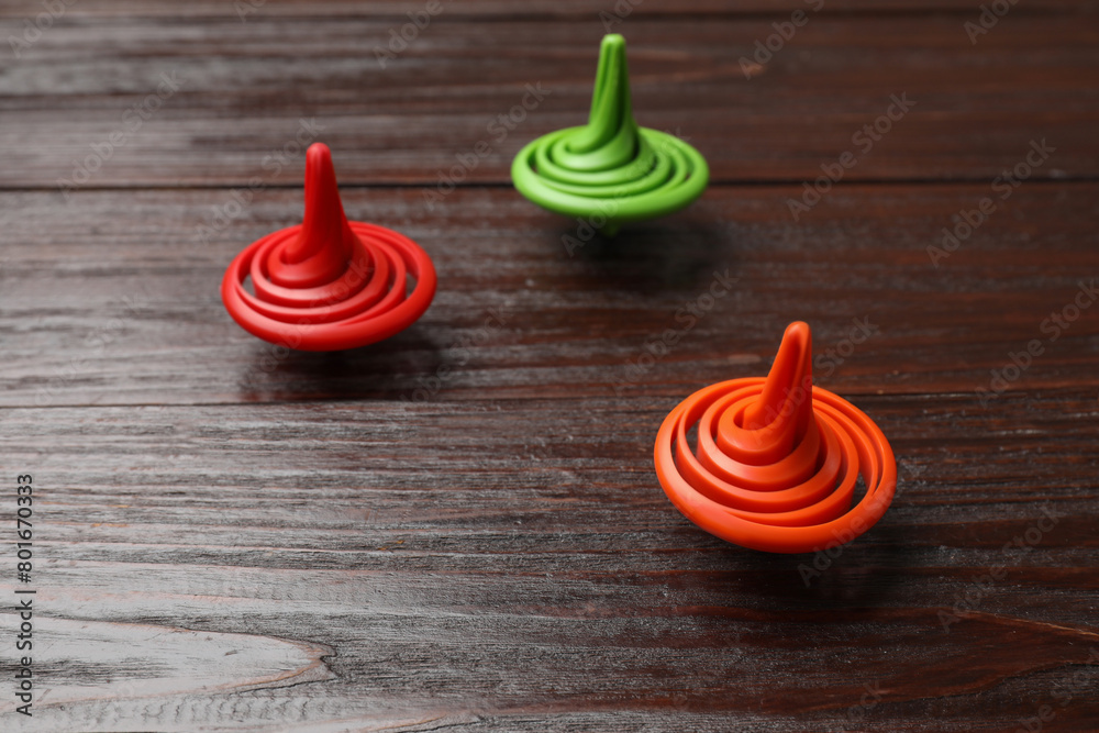 Three bright spinning tops on wooden table Three bright spinning tops on wooden table