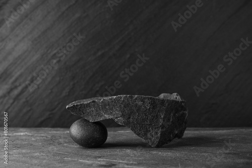 Presentation for product. Podium made of different stones on grey textured background. Space for text