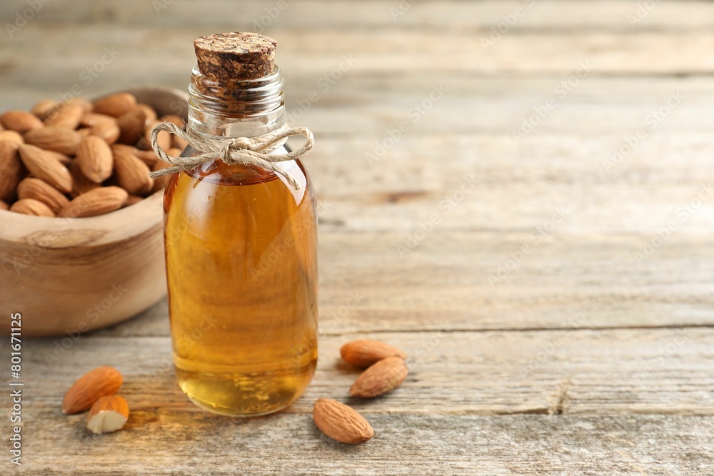 Almond oil in bottle and nuts on wooden table, closeup. Space for text Almond oil in bottle and nuts on wooden table, closeup. Space for text