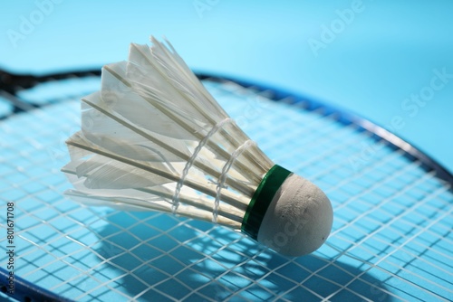 Feather badminton shuttlecock and racket on light blue background, closeup © New Africa