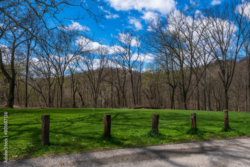 A field in the Regent Square neighborhood of Pittsburgh, Pennsylvania, USA with barriers next to the road in Frick Park on a sunny spring day