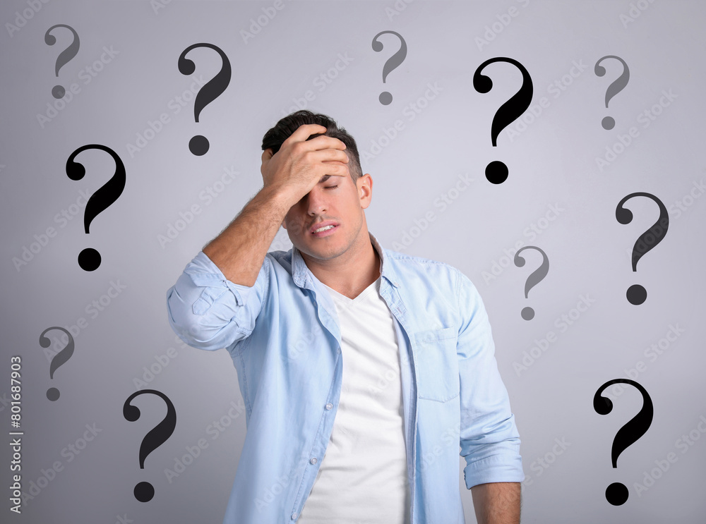 Amnesia. Confused man and question marks on light background Amnesia. Confused man and question marks on light background