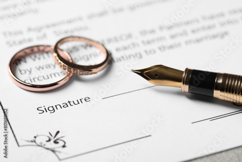 Marriage contract, fountain pen and wedding rings on table, closeup