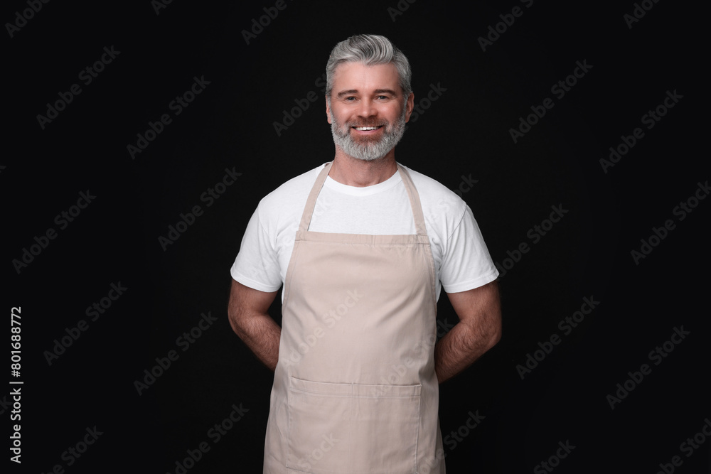 Happy man wearing kitchen apron on black background. Mockup for design Happy man wearing kitchen apron on black background. Mockup for design