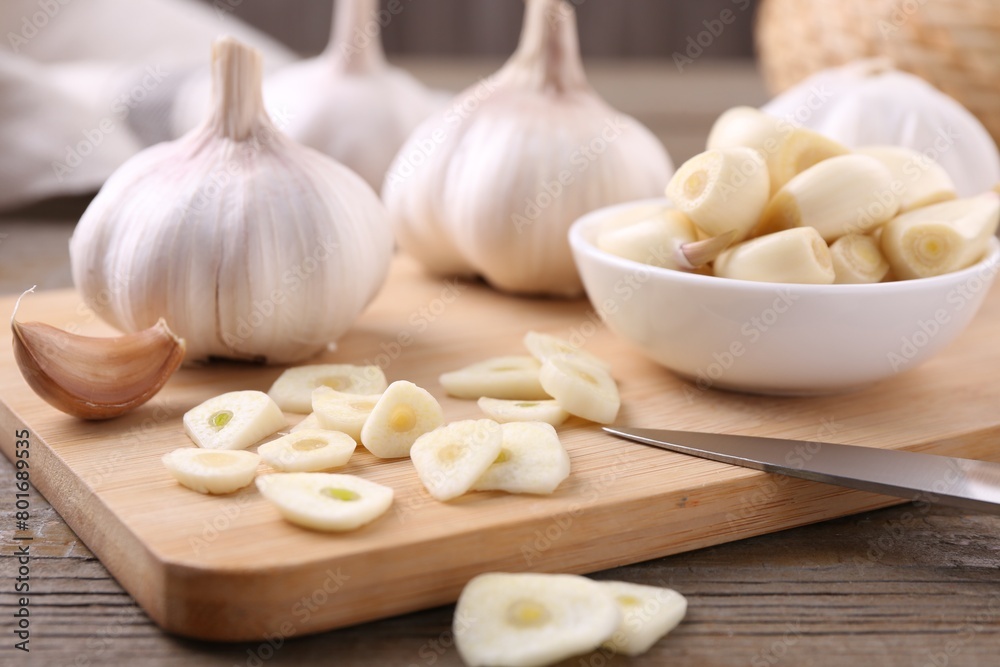 Aromatic cut garlic, cloves and bulbs on wooden table, closeup Aromatic cut garlic, cloves and bulbs on wooden table, closeup