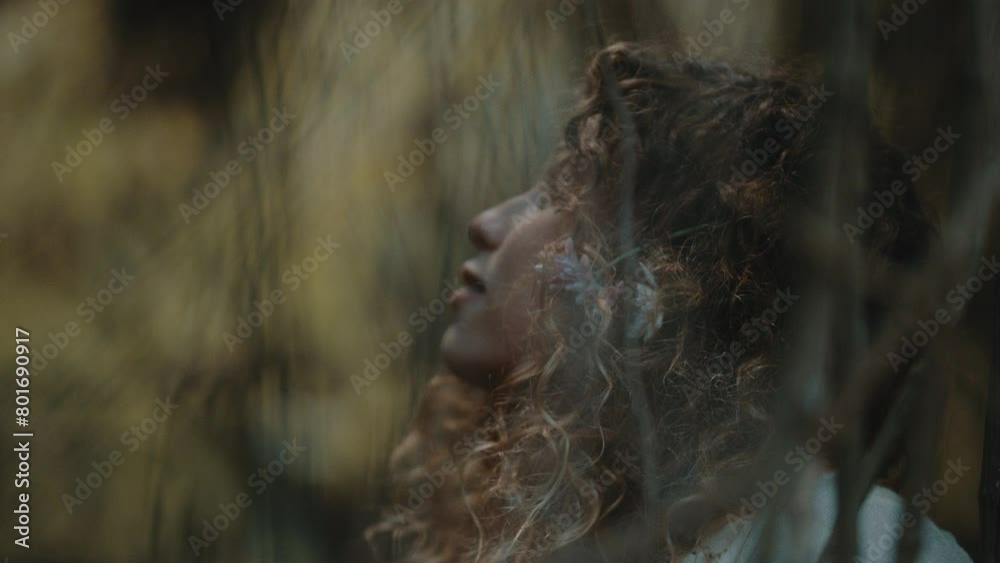 Woman with flowers in hair looking at vines in trees Woman with flowers in hair looking at vines in trees