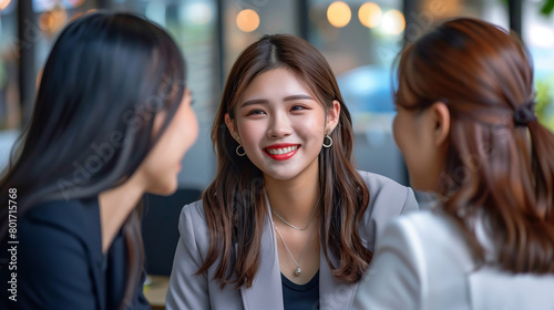Several young Asian business women having a conversation in an office setting
