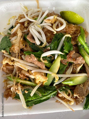 fried noodles with vegetables in a plastic bowl, thai cuisine.