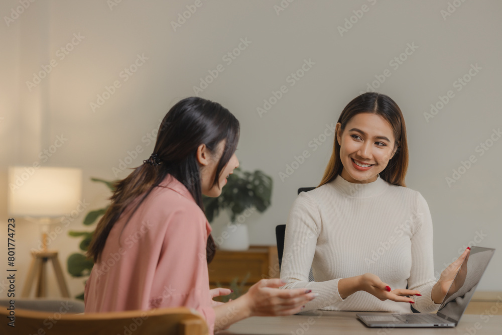 Asian female employees work together at home because they have an important meeting due to the pandemic situation, Two business women working together in their home office having fun and happiness. Asian female employees work together at home because they have an important meeting due to the pandemic situation, Two business women working together in their home office having fun and happiness.