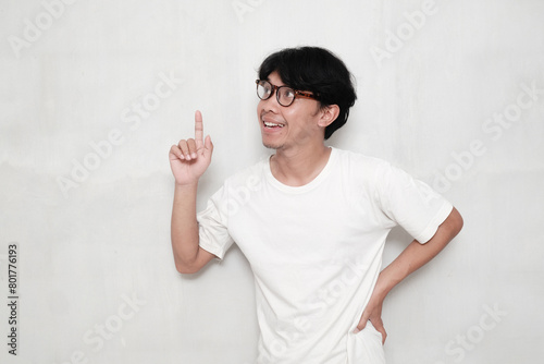 Asian man wearing glasses happy smile point finger at copy space white background photo