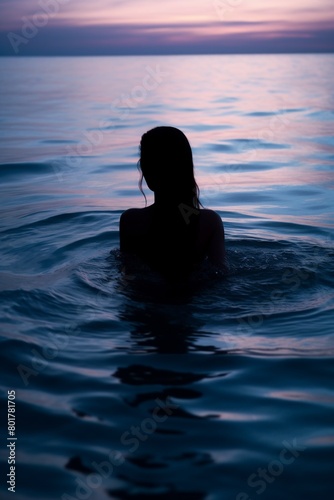 Tranquil scene of a female silhouette from behind, immersed in the calming ripples of the ocean