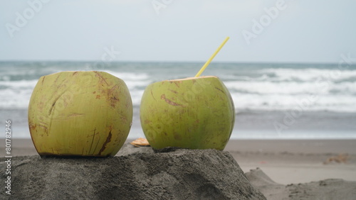 Coconut fruit on beach sand. Blur sand and waves background. Focus selected