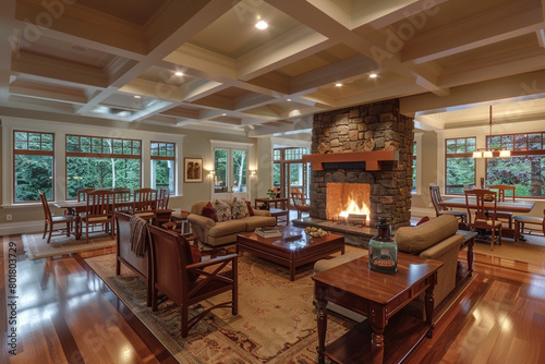 The interior of a craftsman style house featuring an open concept living space with coffered ceilings, a stone fireplace, and handcrafted wooden furniture, bathed in soft, natural light. photo