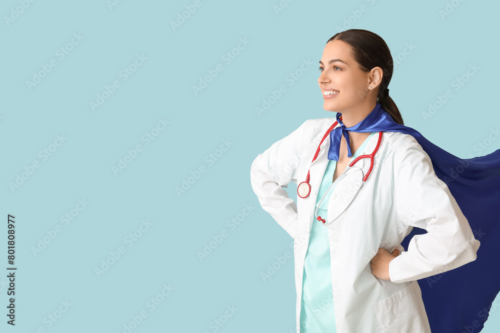 Beautiful female doctor in superhero costume on blue background Beautiful female doctor in superhero costume on blue background