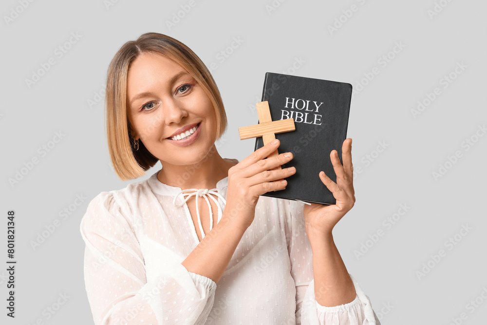 Happy adult woman with Holy Bible and wooden cross on white background Happy adult woman with Holy Bible and wooden cross on white background