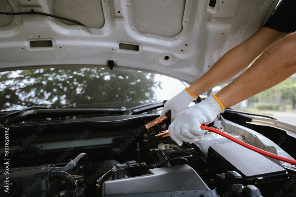 Close-up of auto mechanic charging car battery with electric rail jumper cables Close-up of auto mechanic charging car battery with electric rail jumper cables