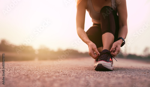 Running shoes, closeup of woman tying shoe laces. Female sport fitness runner getting ready for jogging outdoors photo