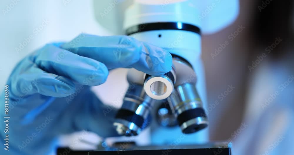 Scientist uses a microscope to study a sample in a laboratory Scientist uses a microscope to study a sample in a laboratory