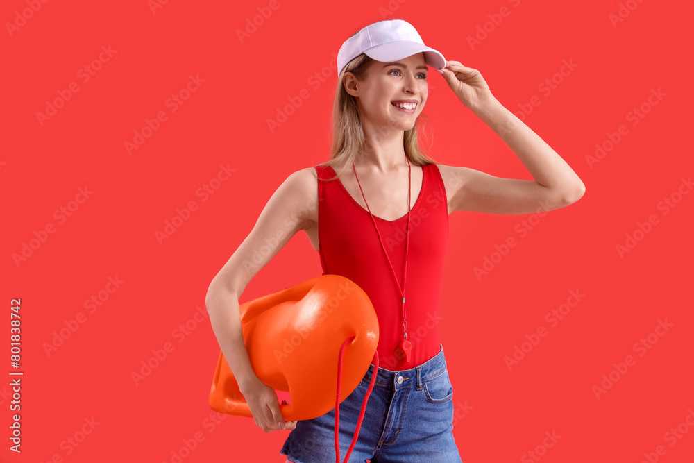 Young female lifeguard in cap with buoy on red background Young female lifeguard in cap with buoy on red background