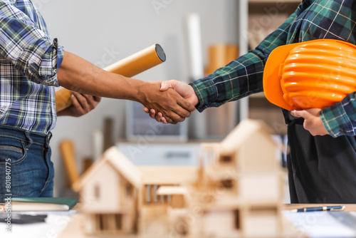 Young Asian forewoman and middle-aged foreman, achieving success through agreement and teamwork, symbolized by a handshake. Expertise in budgeting, design, and architectural planning. photo