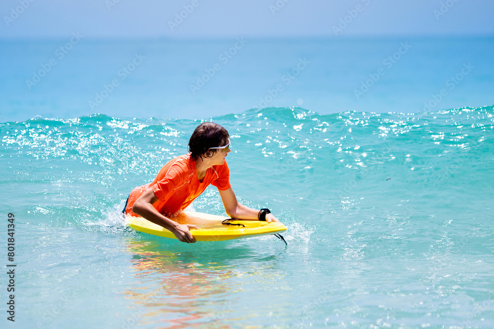 Child surfing on tropical beach. Surfer in ocean. Child surfing on tropical beach. Surfer in ocean.