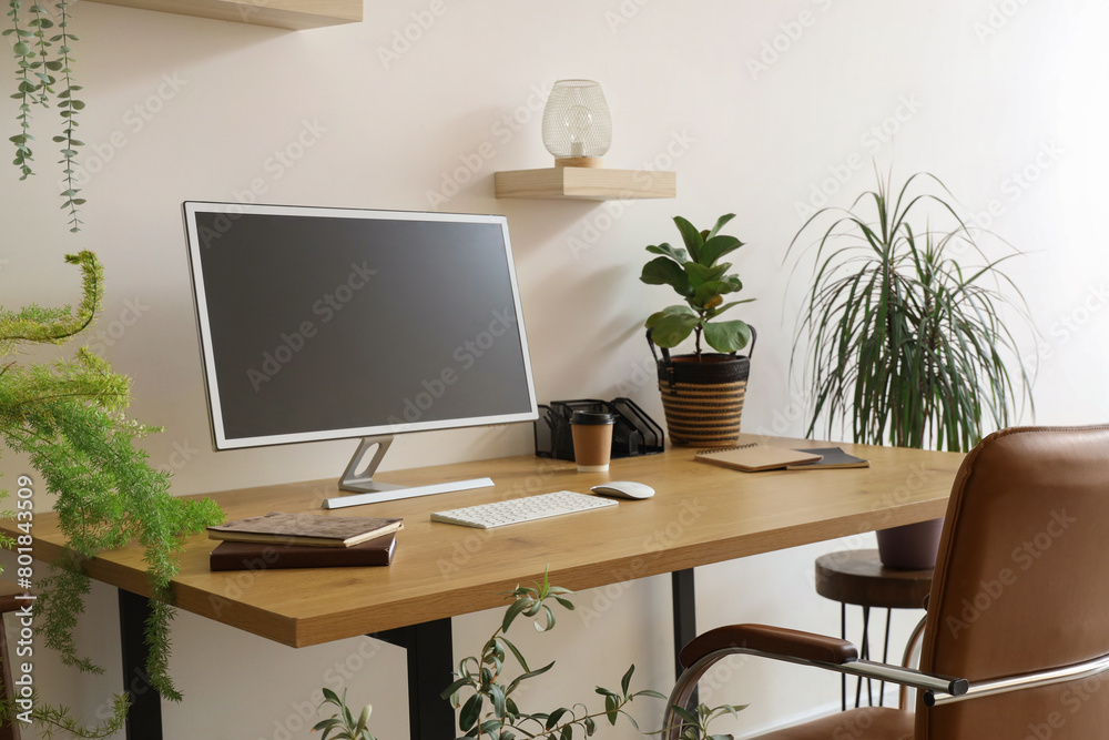 Modern workplace with computer monitor and houseplants near light wall in office Modern workplace with computer monitor and houseplants near light wall in office