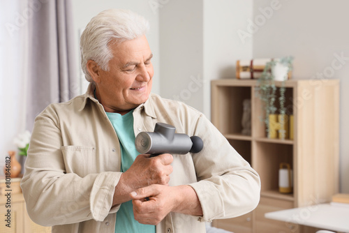 Wallpaper Mural Mature man massaging his shoulder with percussive massager at home Torontodigital.ca