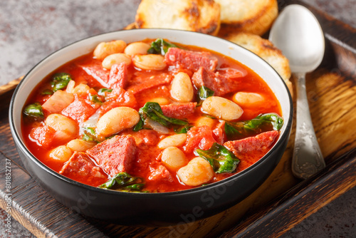 Spanish stew of butter beans, chorizo and spinach in tomato sauce close-up in a bowl on the table. Horizontal